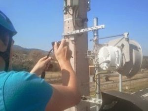 Technicien CF31 réglant le support d'une antenne de faisceau hertzien en hauteur