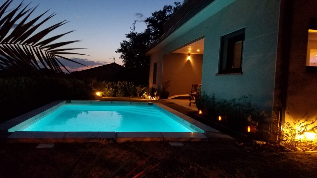 Éclairage LED immergé de piscine et spots extérieurs sur terrasse couverte