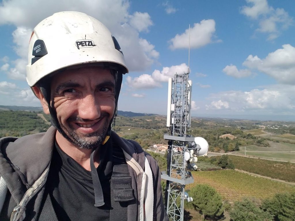 Technicien en hauteur sur pylône télécom équipé d'antennes faisceaux hertziens