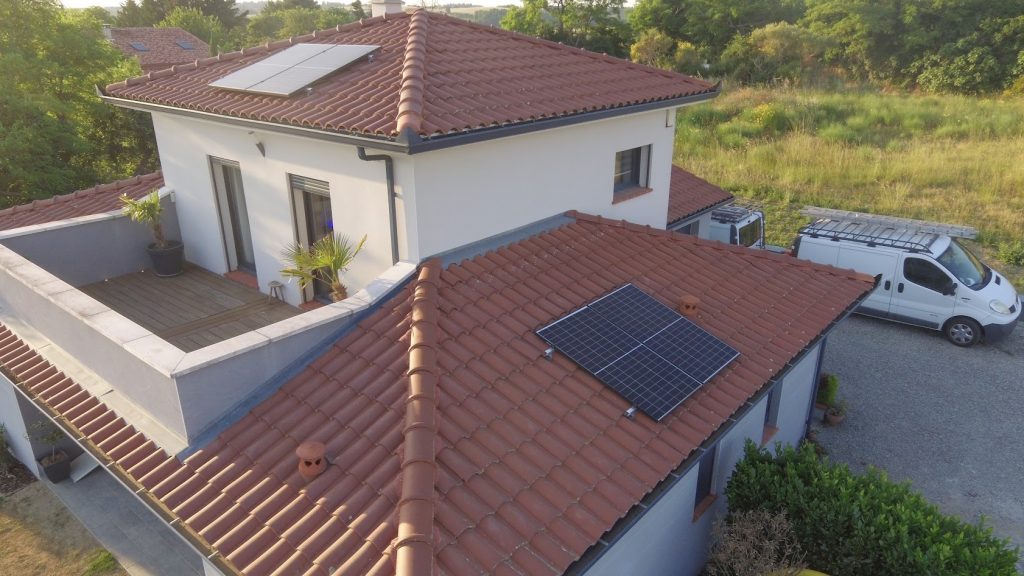 Maison avec toiture en croupe et panneau photovoltaïque, fourgons techniciens sur site