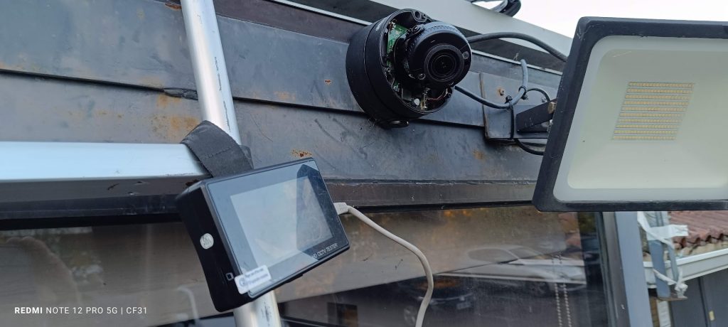 Installation d'une caméra dôme de vidéosurveillance avec testeur CCTV portable sur chantier