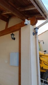 Caméra dôme de vidéosurveillance extérieure fixée sous un auvent en bois à l'angle d'un bâtiment